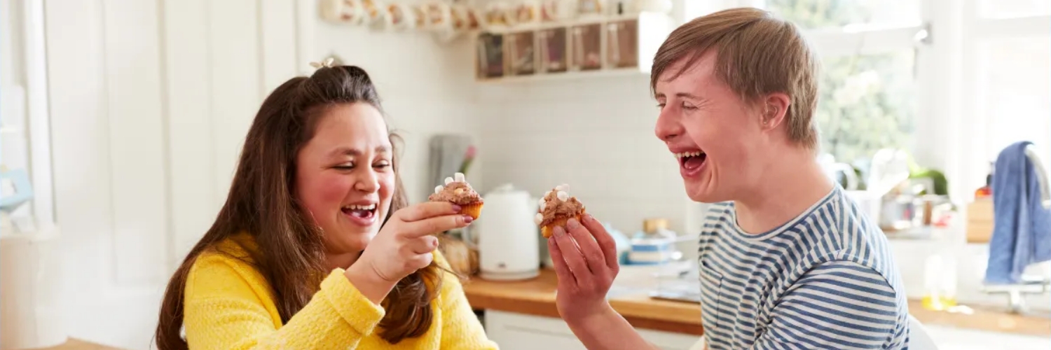 A young woman and man smiling in a kitchen