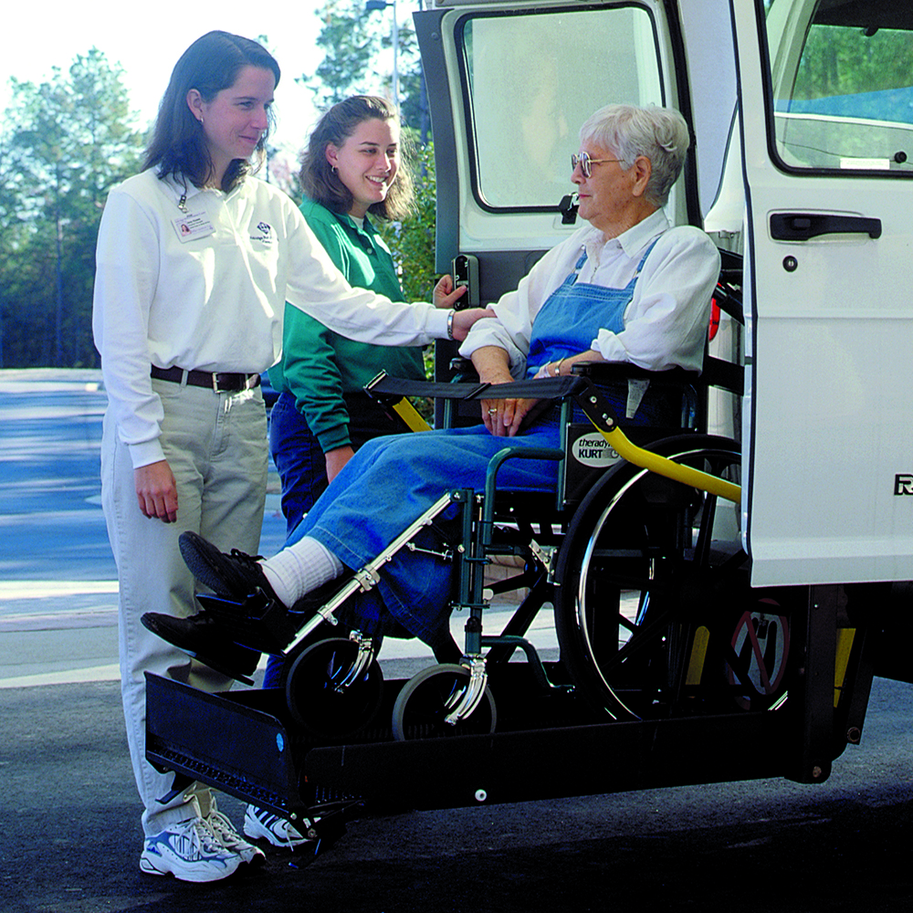 woman in wheelchair being helped into a van