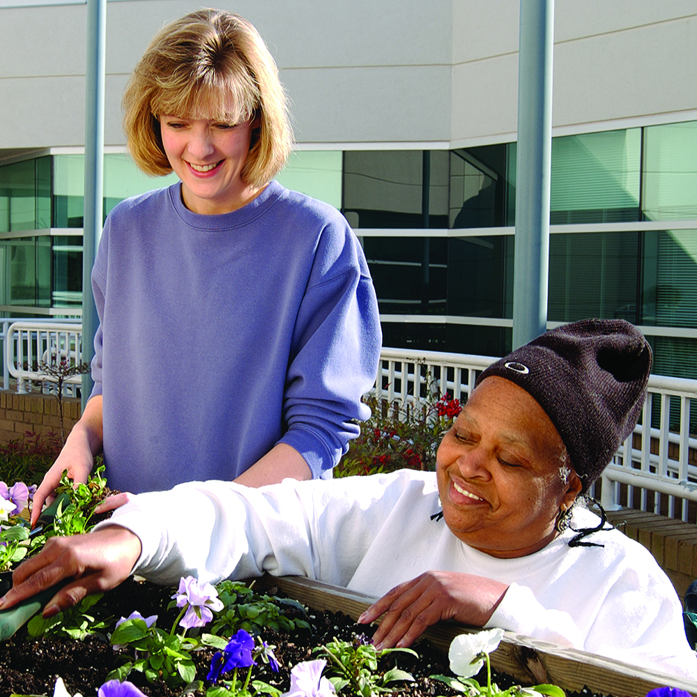 a woman standing with another smiling woman gardening