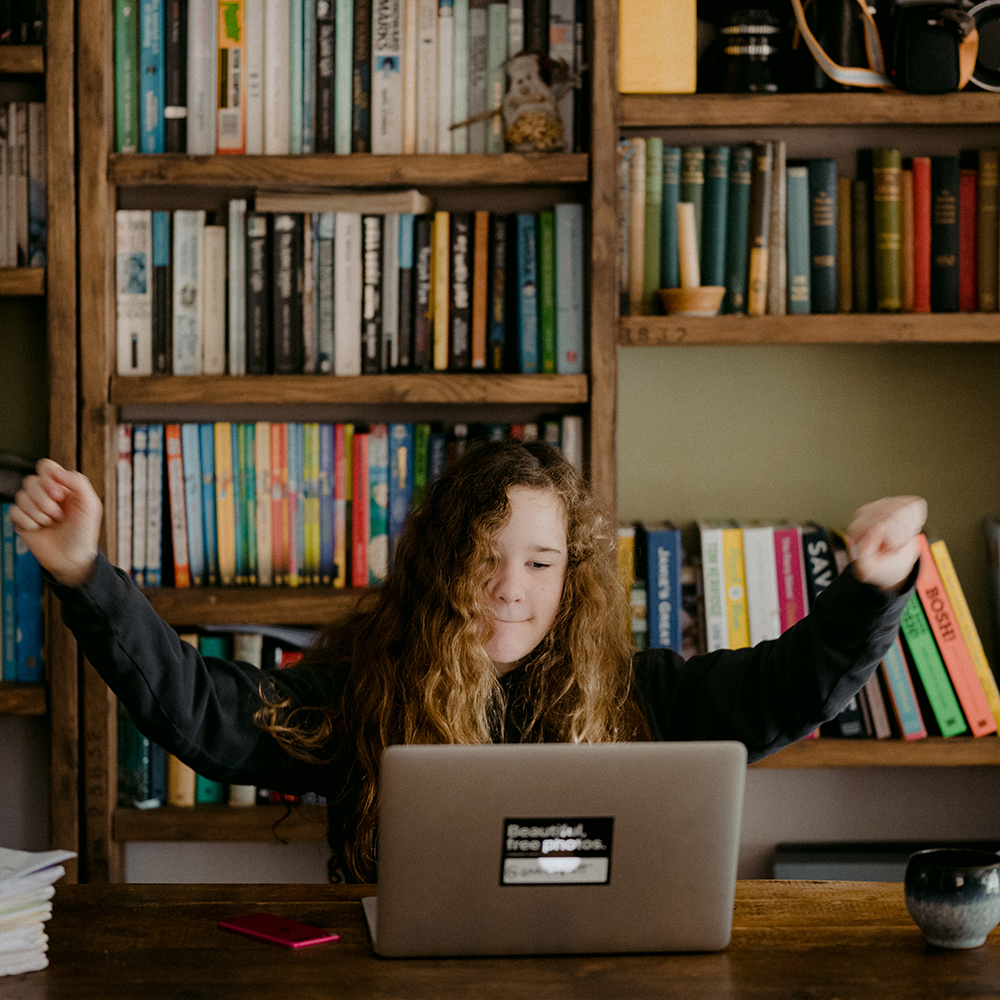 girl raising fists in accomplishment at computer