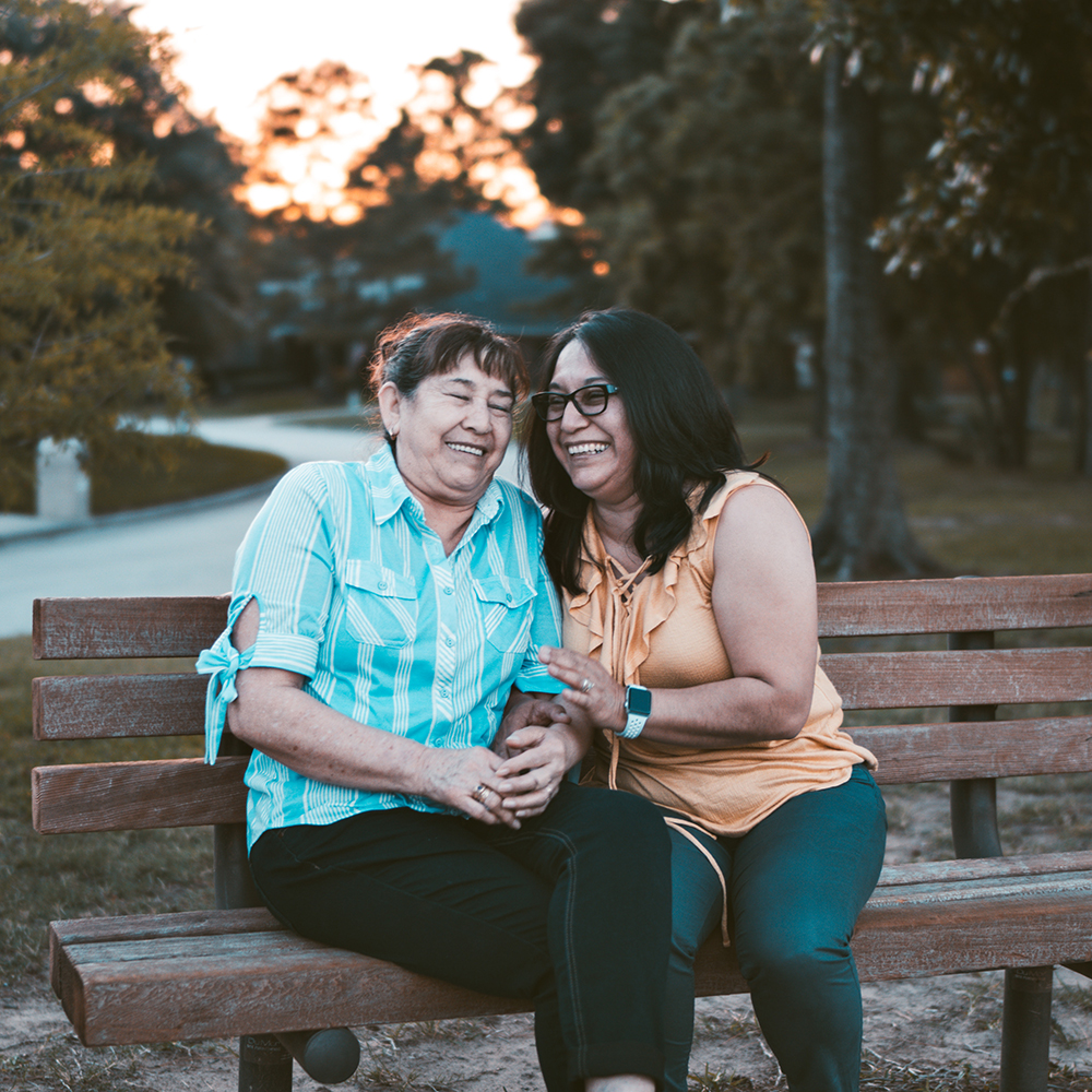 woman and her mother smiling on a bench
