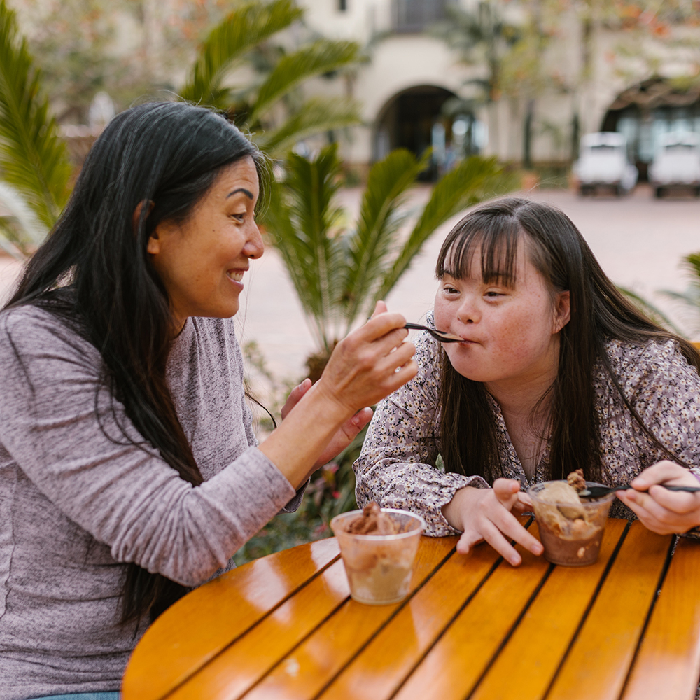 woman feeding ice cream to girl