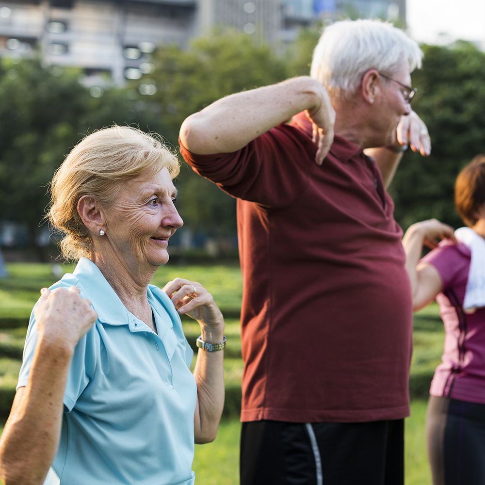 elderly woman and man stretching in a park