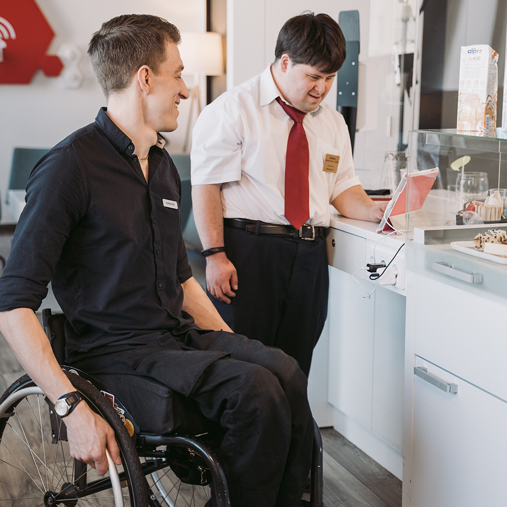 man in wheelchair and young man in coffee shop
